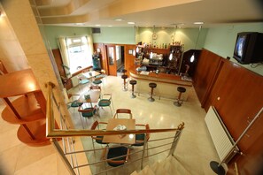 A bar area with stools, a counter, and a television. - Hotel Ramos (Silleda)