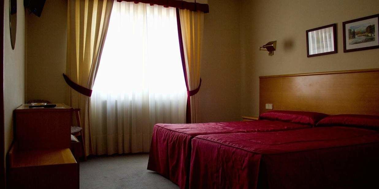 A hotel room with a bed, a desk, and a chair.