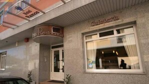L’entrée d’un hôtel, avec une enseigne indiquant « Hôtel Ramoss Residencia » et une fenêtre sur laquelle est affiché le mot « Cafétéria ».