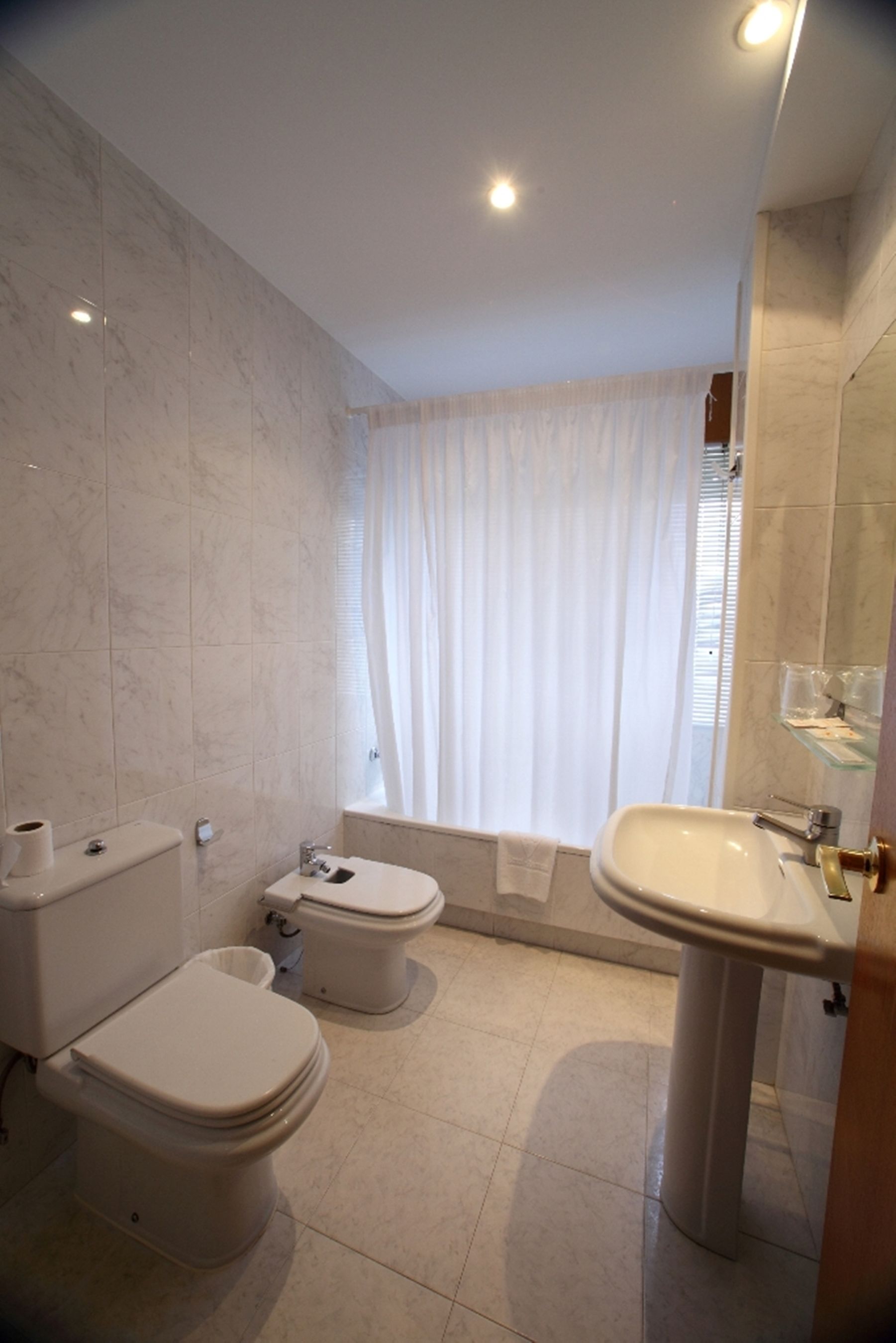 Un bagno con due servizi igienici, un lavandino e una doccia.