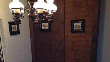 Une table de salle à manger ronde, dressée pour quatre personnes, avec des nappes blanches, des assiettes, des couverts et des verres. Deux luminaires sont fixés au mur au-dessus de la table.