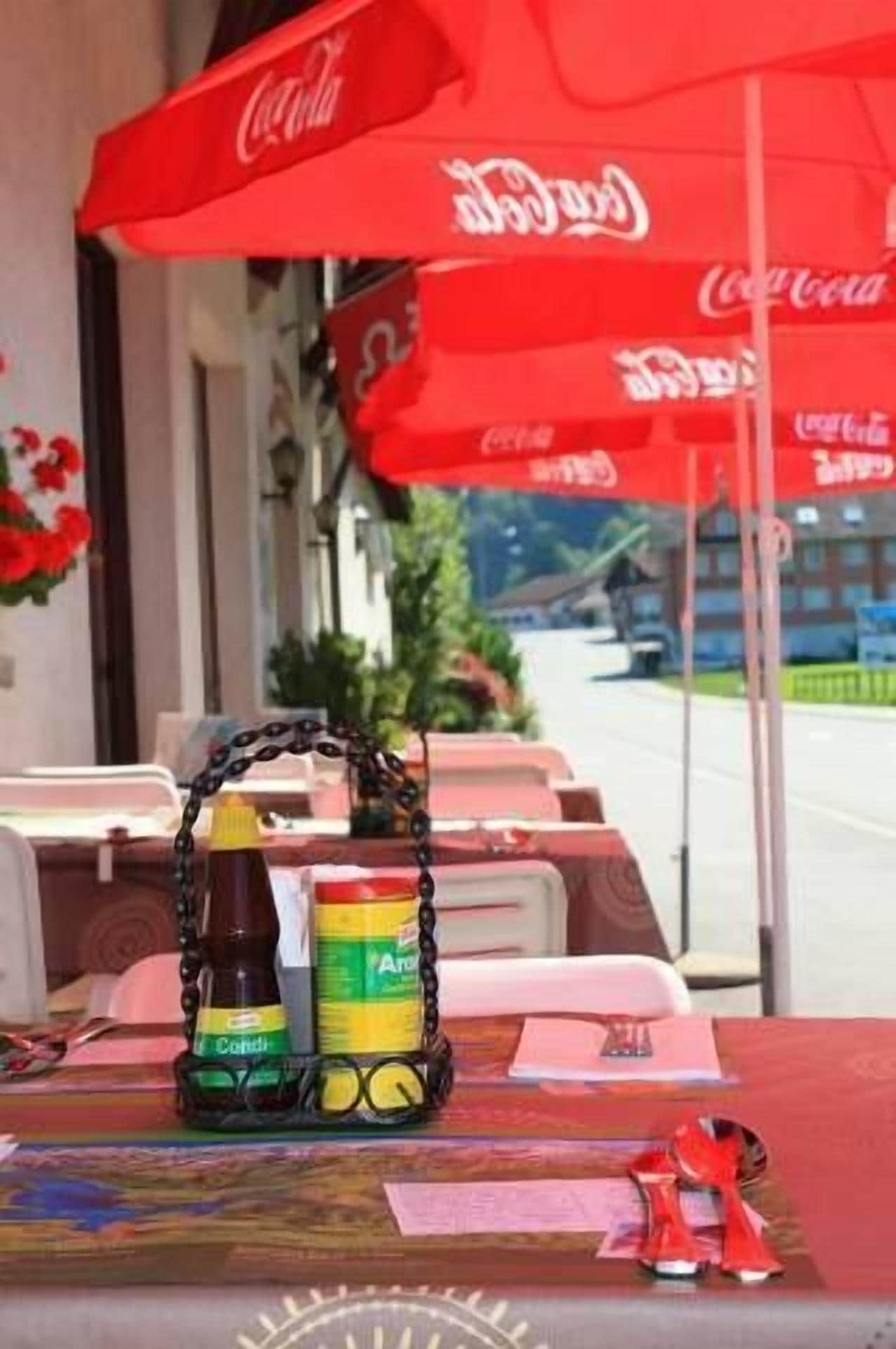 Une table avec un parasol à l’effigie de Coca-Cola, une bouteille de Coca-Cola et une canette de Coca-Cola.