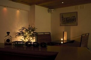 Un comedor con una mesa, sillas, una planta en maceta, una botella y un cuadro en la pared.