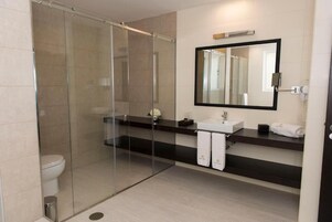 Un baño moderno con cabina de ducha de vidrio, un lavamanos con espejo y un inodoro.
