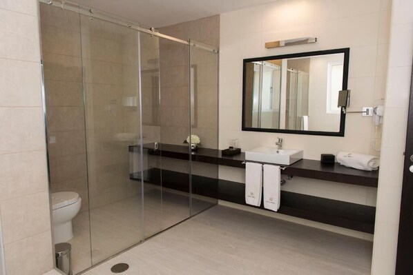 Un baño moderno con cabina de ducha de vidrio, un lavamanos con espejo y un inodoro.
