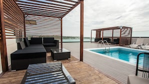 Una terraza en la azotea con piscina, asientos al aire libre y vistas a la ciudad.