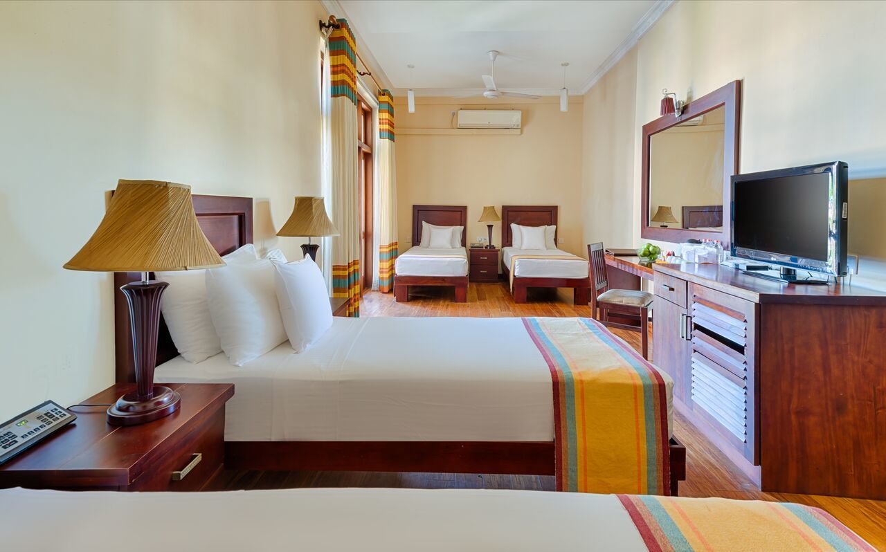 A hotel room with two beds, a TV, a desk, and a wardrobe.