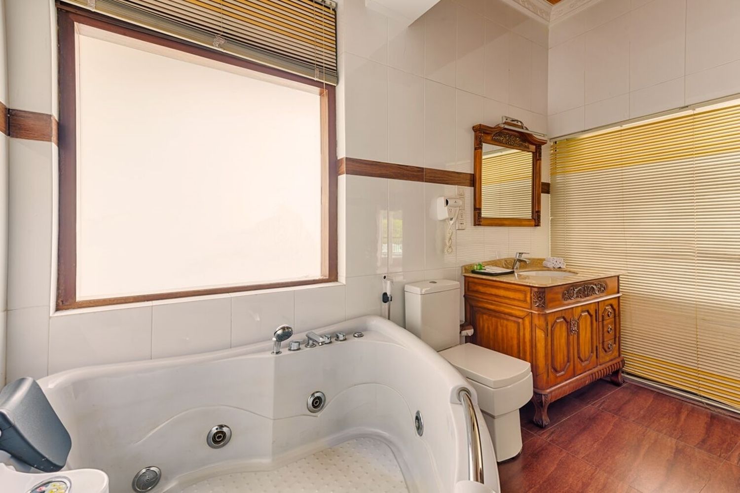 A bathroom with a large bathtub, wooden vanity, and a mirror.