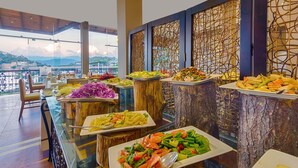A buffet with various dishes, wooden tables, and a view of the mountains. - Serene Kandy (Kandy)