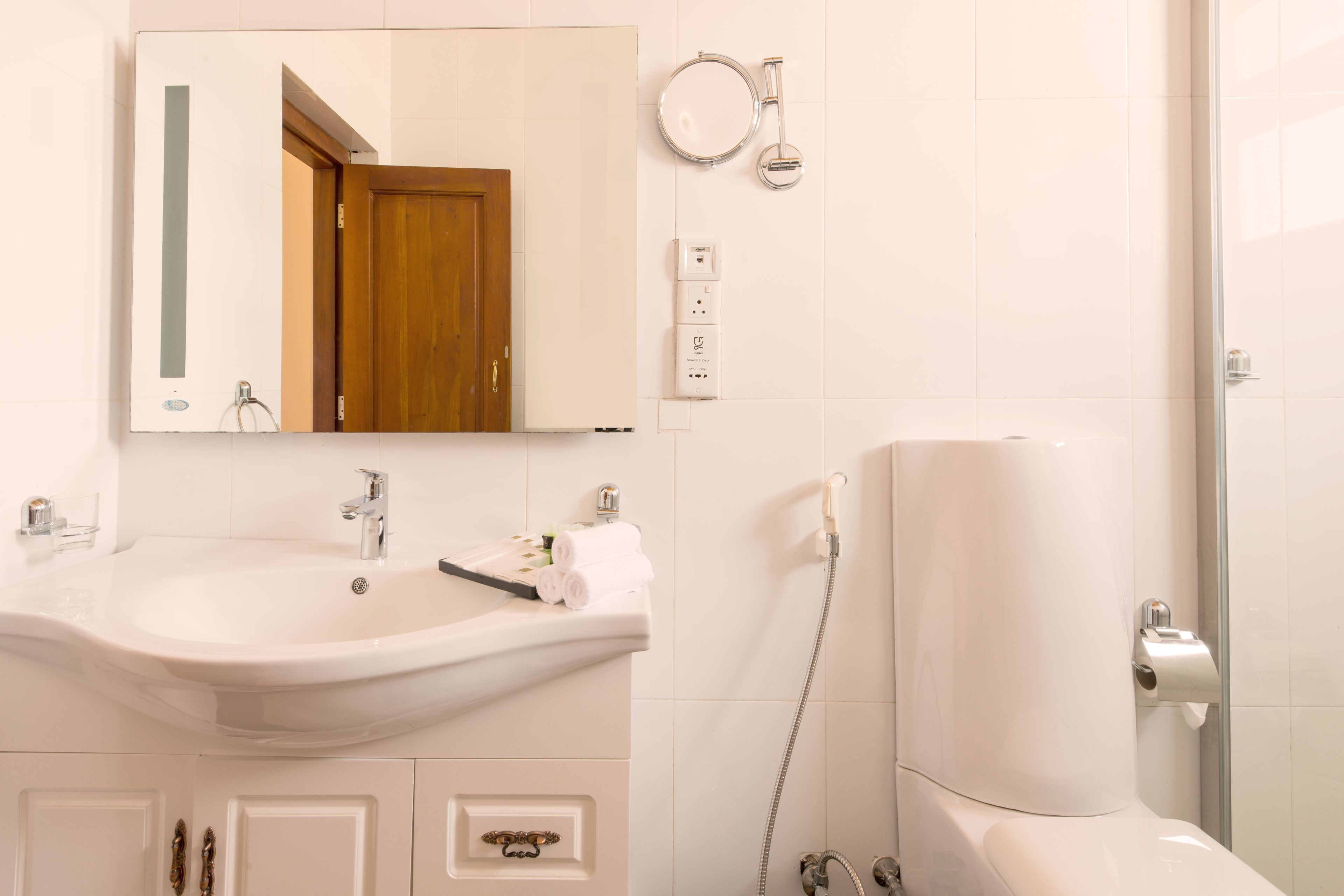 Un baño con lavamanos, espejo e inodoro.