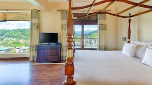 A four-poster bed in a room with a balcony, a television, and a view of a green landscape. - Serene Kandy (Kandy)