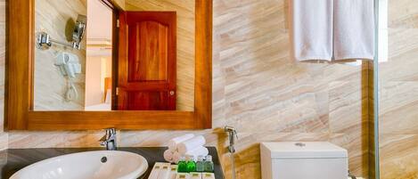 A bathroom with a large mirror, a sink, a toilet, and a towel rack.