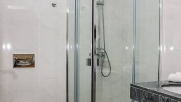 A modern bathroom with a glass-enclosed shower, a white toilet, and a marble-tiled floor.