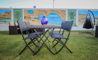 Un comedor con una mesa y sillas, un jarrón decorativo y un mural de fondo.