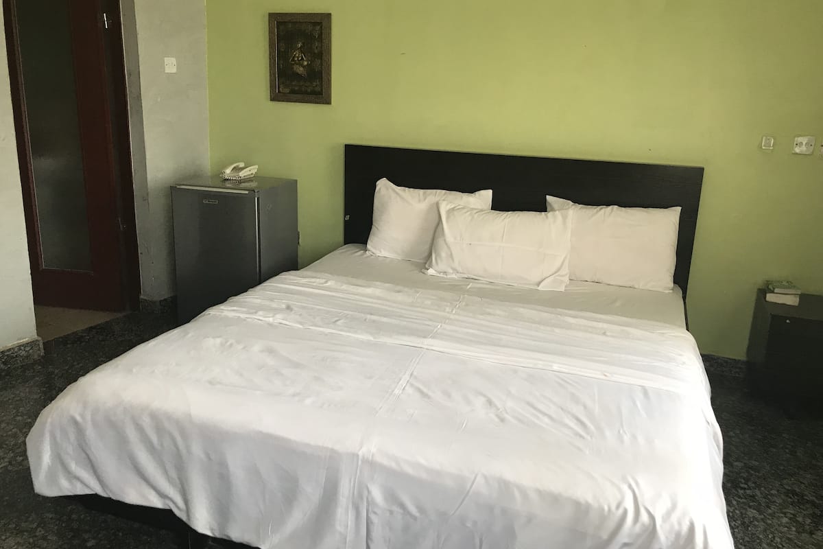 Een hotelkamer met een groot bed, een klein bureau, een telefoon en een foto aan de muur.