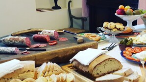 Noutopöytä, jossa on tarjolla monenlaista ruokaa, kuten viipaloitua leipää, juustoa ja erilaisia lihaleikkeleitä.