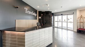 Una recepción con diseño moderno, un letrero que dice "Travelodge" y una puerta de cristal de acceso.