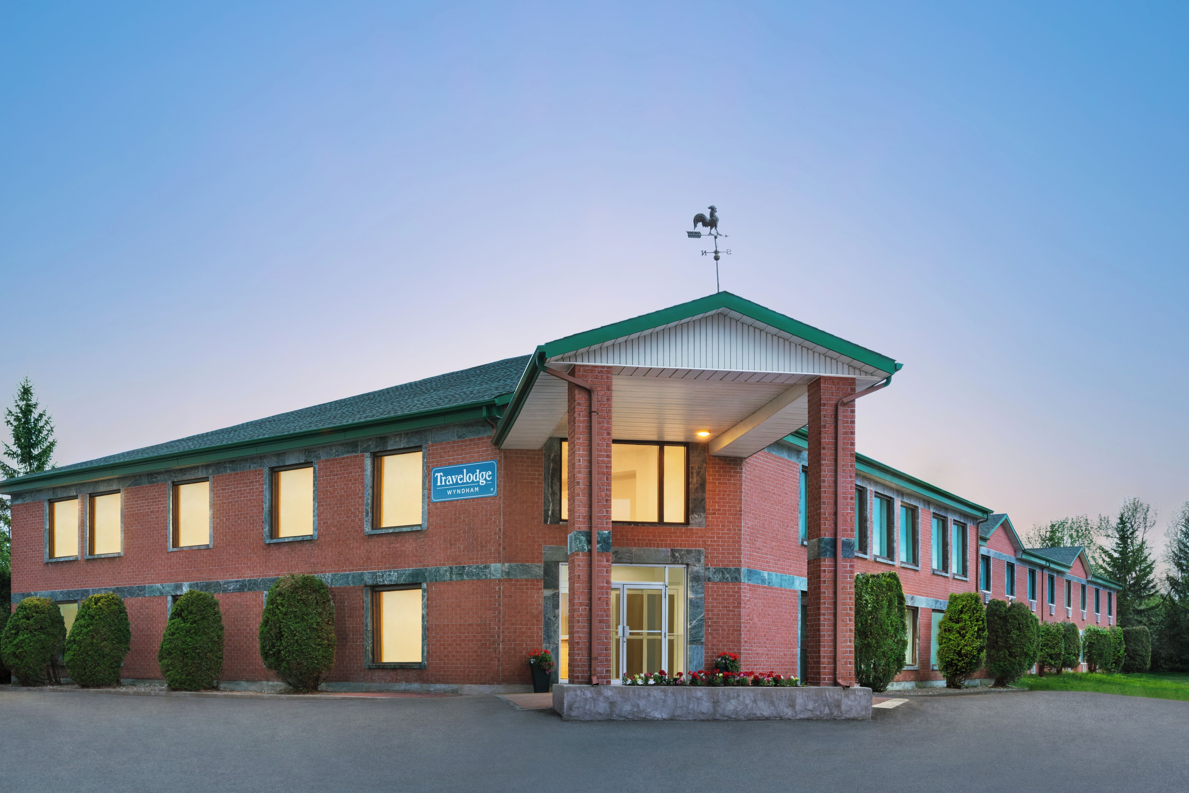 A brick building with a green roof and a covered entrance. A sign indicates it's a Travelodge.