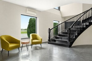 A modern interior with a staircase, two armchairs, and a round table.