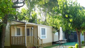 A mobile home with a porch, a small deck, and a green lawn area. - Camping El Camell (Pineda de Mar)