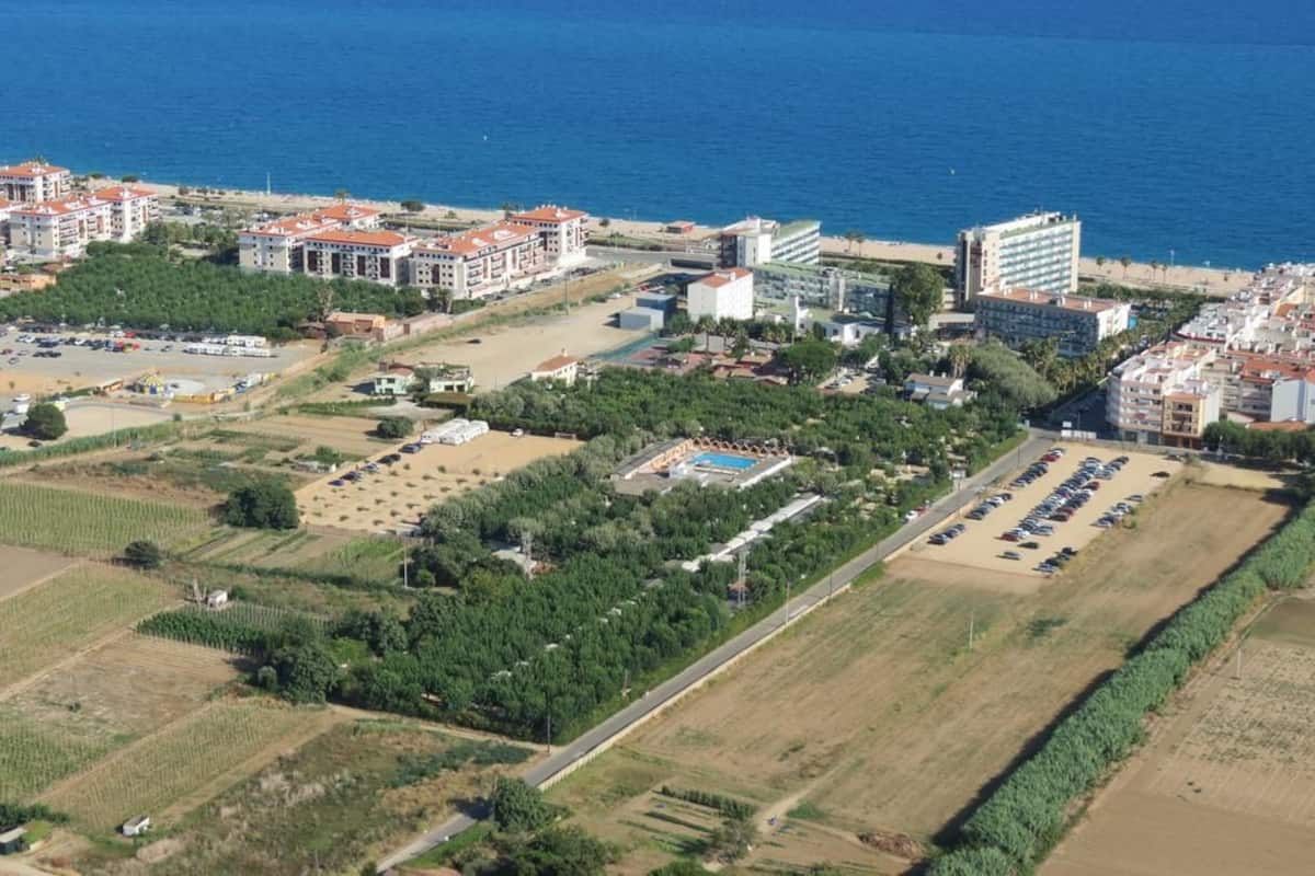 Vue aérienne d’une zone côtière avec des bâtiments, une plage et un parking.