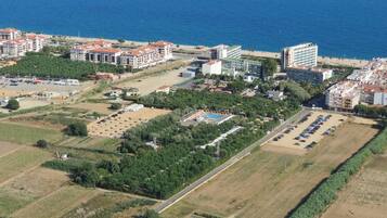 Vista aérea de una zona costera con edificios, una playa y un estacionamiento.