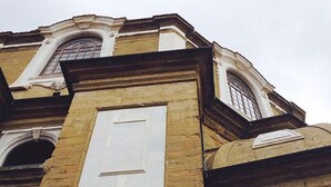 Un edificio con una puerta blanca central destacada, ventanas arqueadas y fachada de piedra.