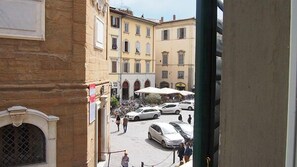 A courtyard with parked cars, a few people walking, and buildings with arched windows and balconies. - Locanda il Salimbecco (Florence)