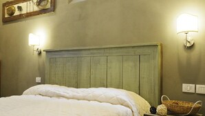 Una cama bien hecha con un edredón acolchado, un cabecero de madera y dos lámparas fijadas a la pared.