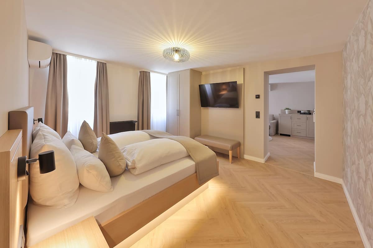Ein modernes Schlafzimmer mit Bett, Nachttisch und einem an der Wand montierten Fernseher.