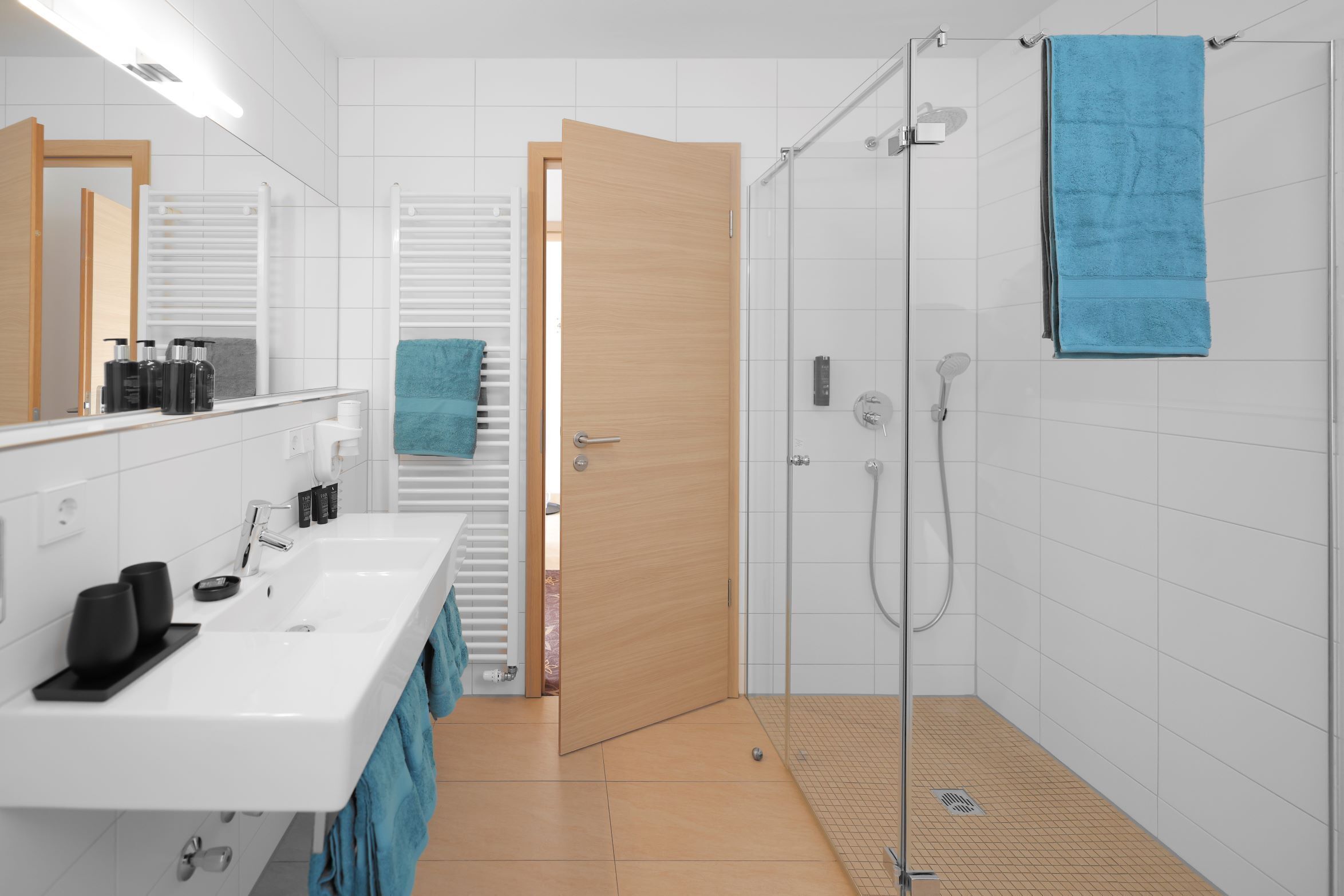 A modern bathroom with a white sink, two mirrors, a shower, and a towel rack.