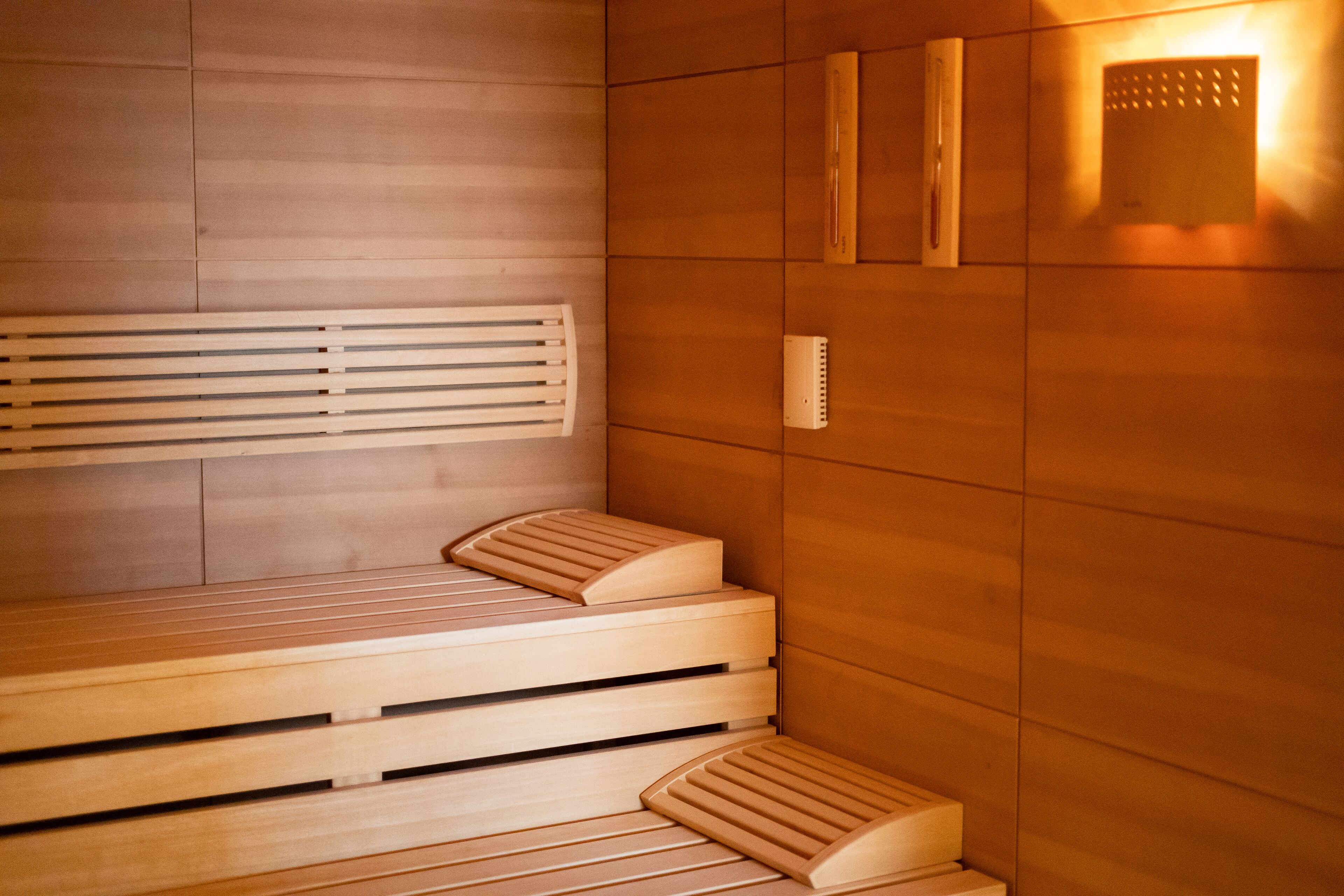 Een sauna met houten banken en een bank met voetsteun.