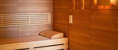 Una sauna con bancos de madera y un banco con reposapiés.