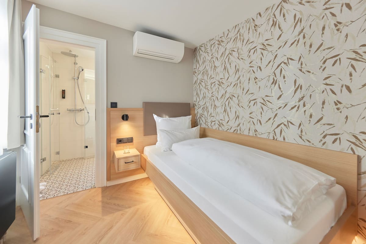 Ein Hotelzimmer mit einem hölzernen Bett, einer Duschkabine und einer Wand mit Muster.