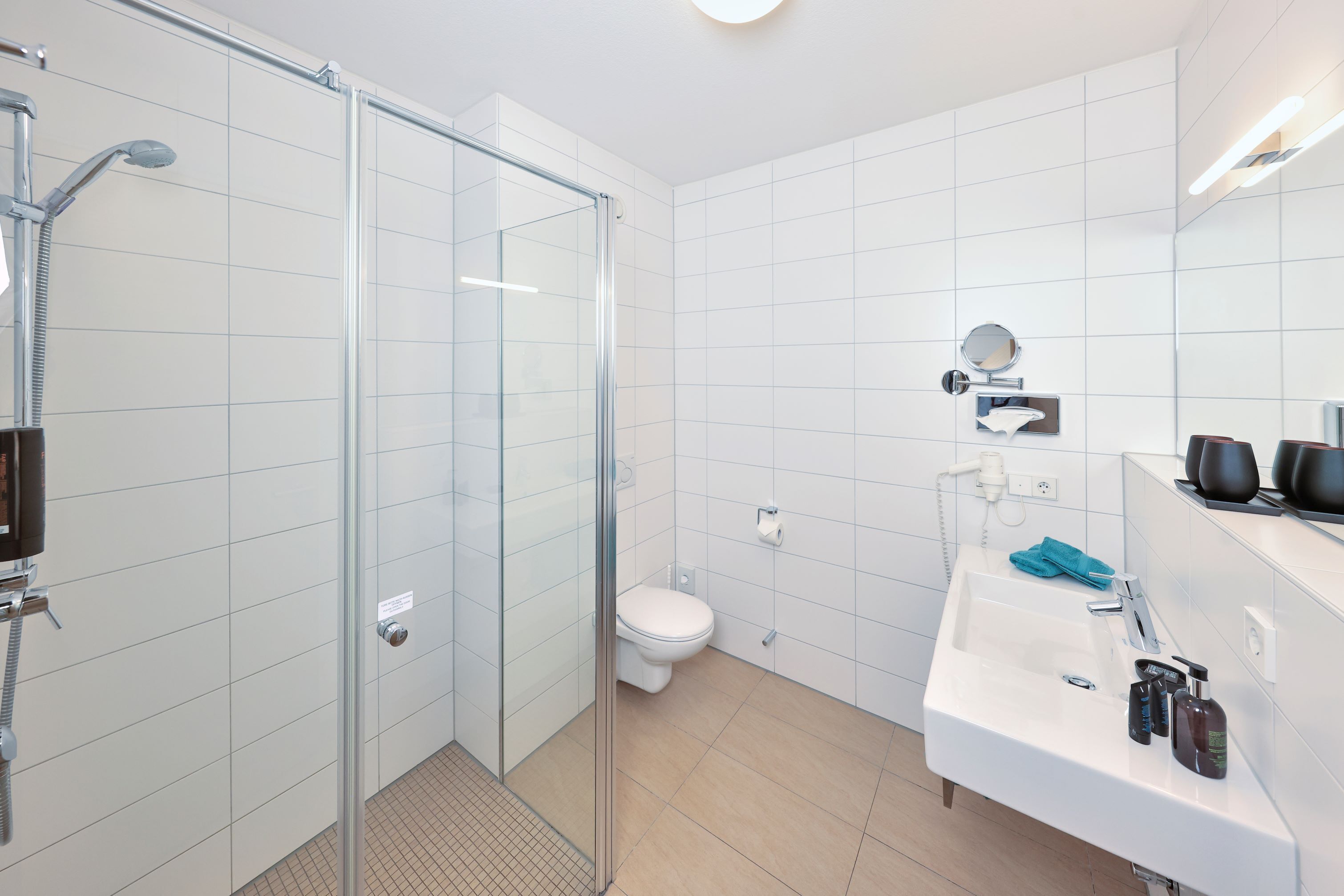 Un bagno moderno con cabina doccia in vetro, lavandino bianco con articoli da toilette e un water.