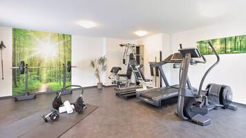 A gym with a treadmill, elliptical, and weight bench.