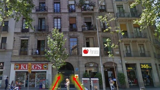 A multi-story building with various storefronts, including a pharmacy and a restaurant. - Hostal Paraiso (Barcelona)