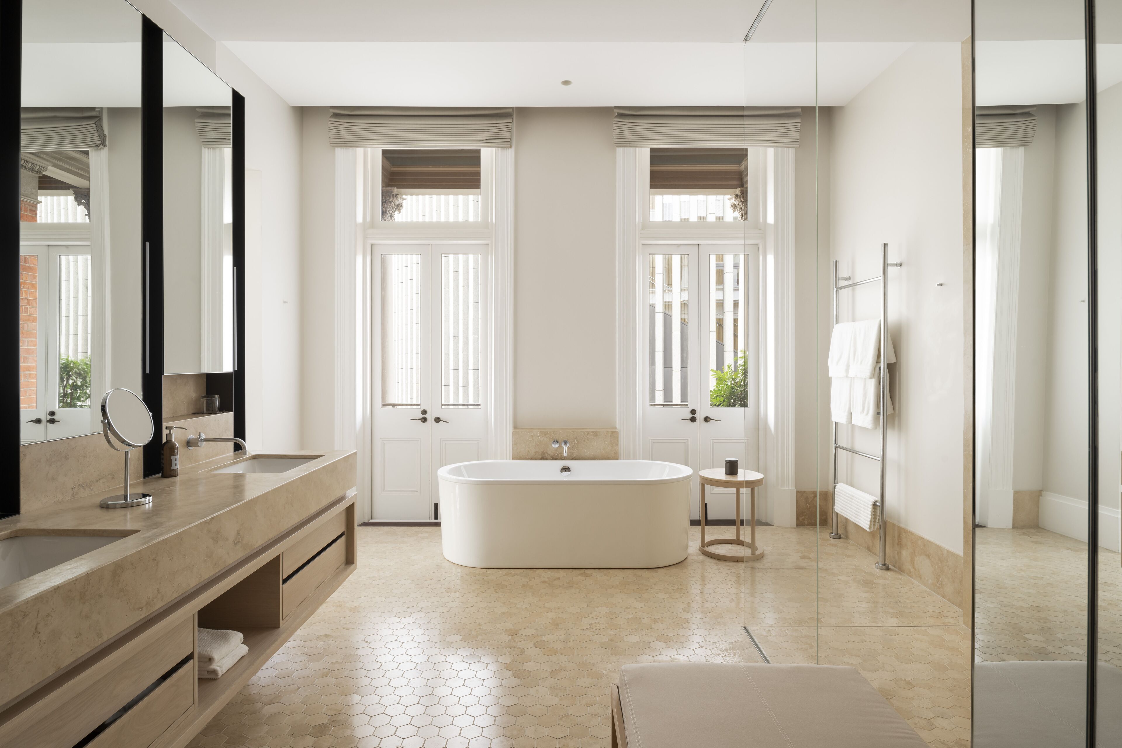 Un baño moderno con una bañera grande, dos lavamanos, un tocador y un espejo amplio.