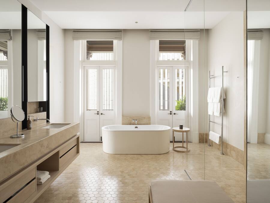 Un baño moderno con una bañera grande, dos lavamanos, un tocador y un espejo amplio.