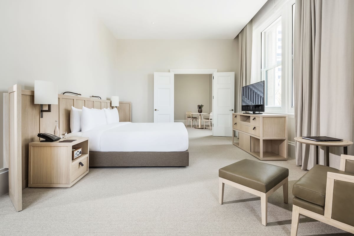 Ein modernes Hotelzimmer mit einem großen Bett, Nachttischen, einem Fernseher und einer Sitzecke.