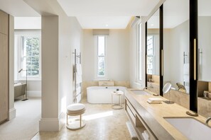 A modern bathroom with a freestanding bathtub, a large vanity with a mirror, and a separate toilet.