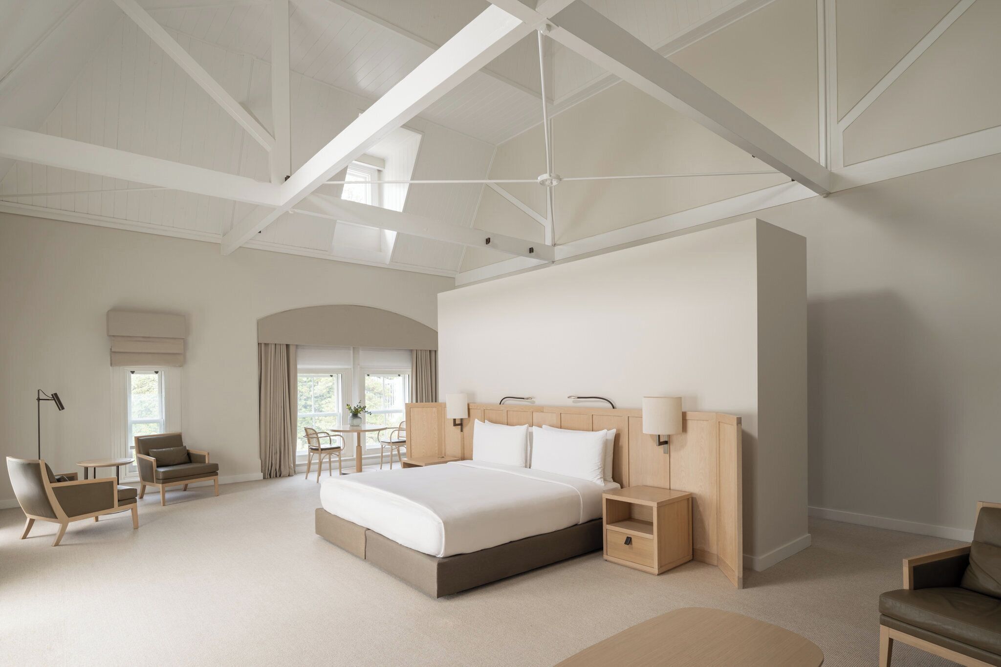 A spacious hotel room with a large bed, two bedside tables, a desk, and a chair.