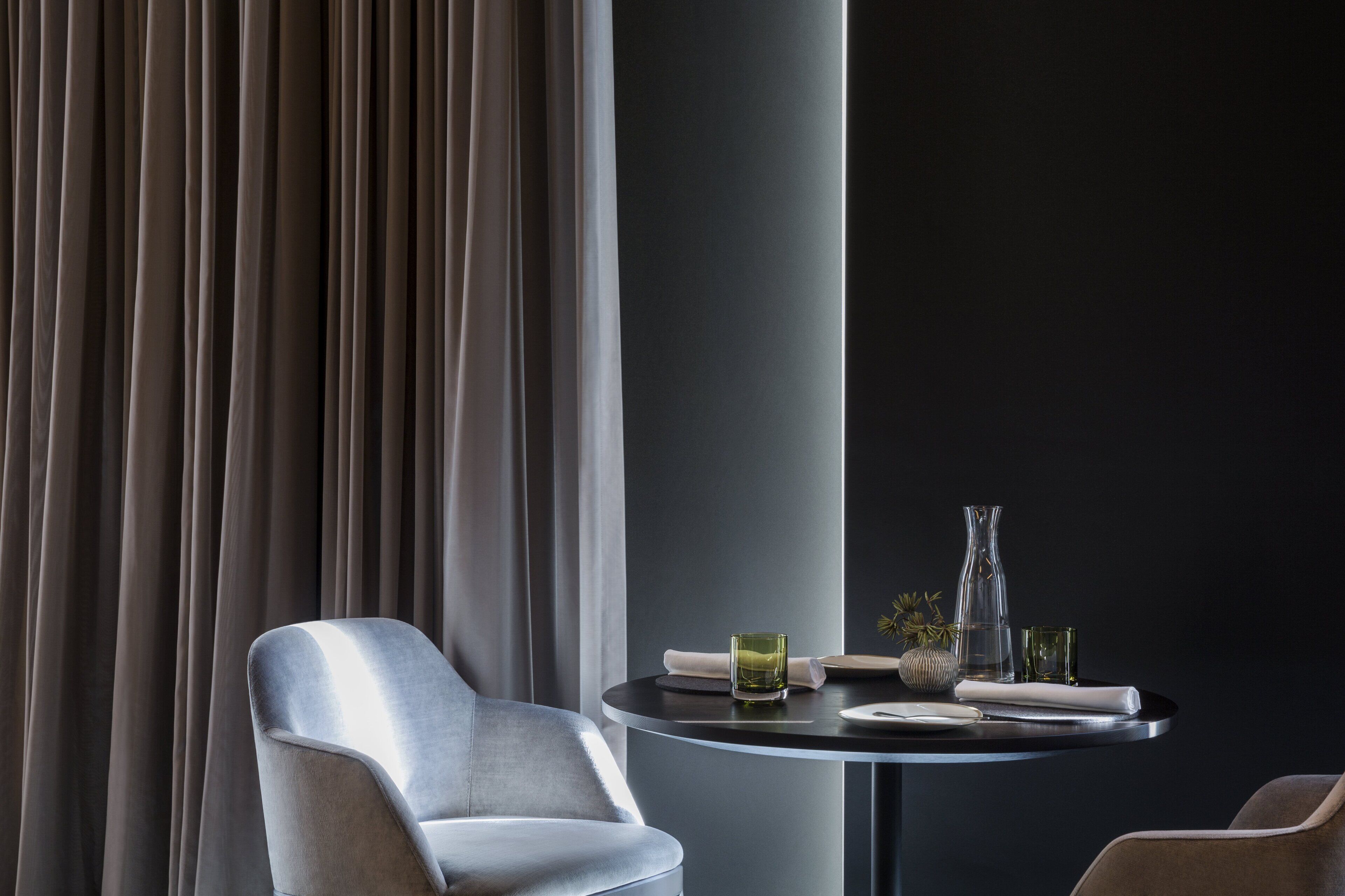 A modern dining area with a round table, a chair, and a vase.