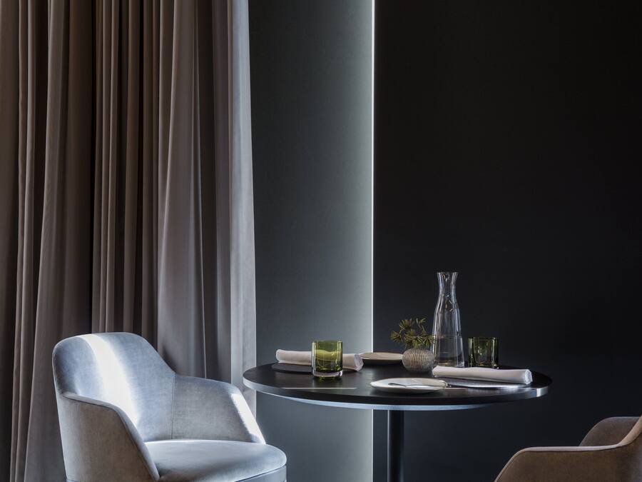 A modern dining area with a round table, a chair, and a vase.
