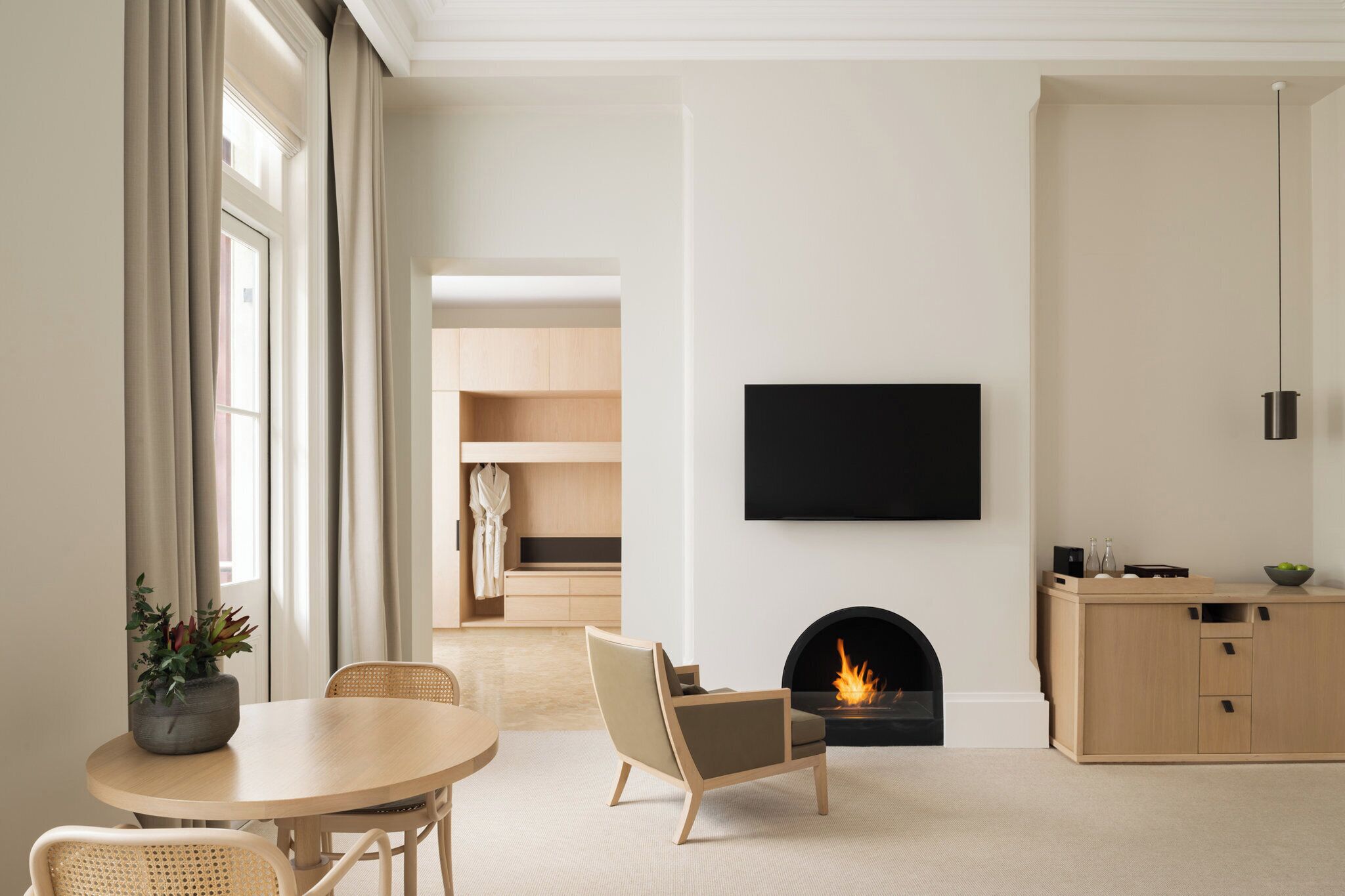 A modern living room with a fireplace, a flat-screen TV, and a dining area with a table and chairs.