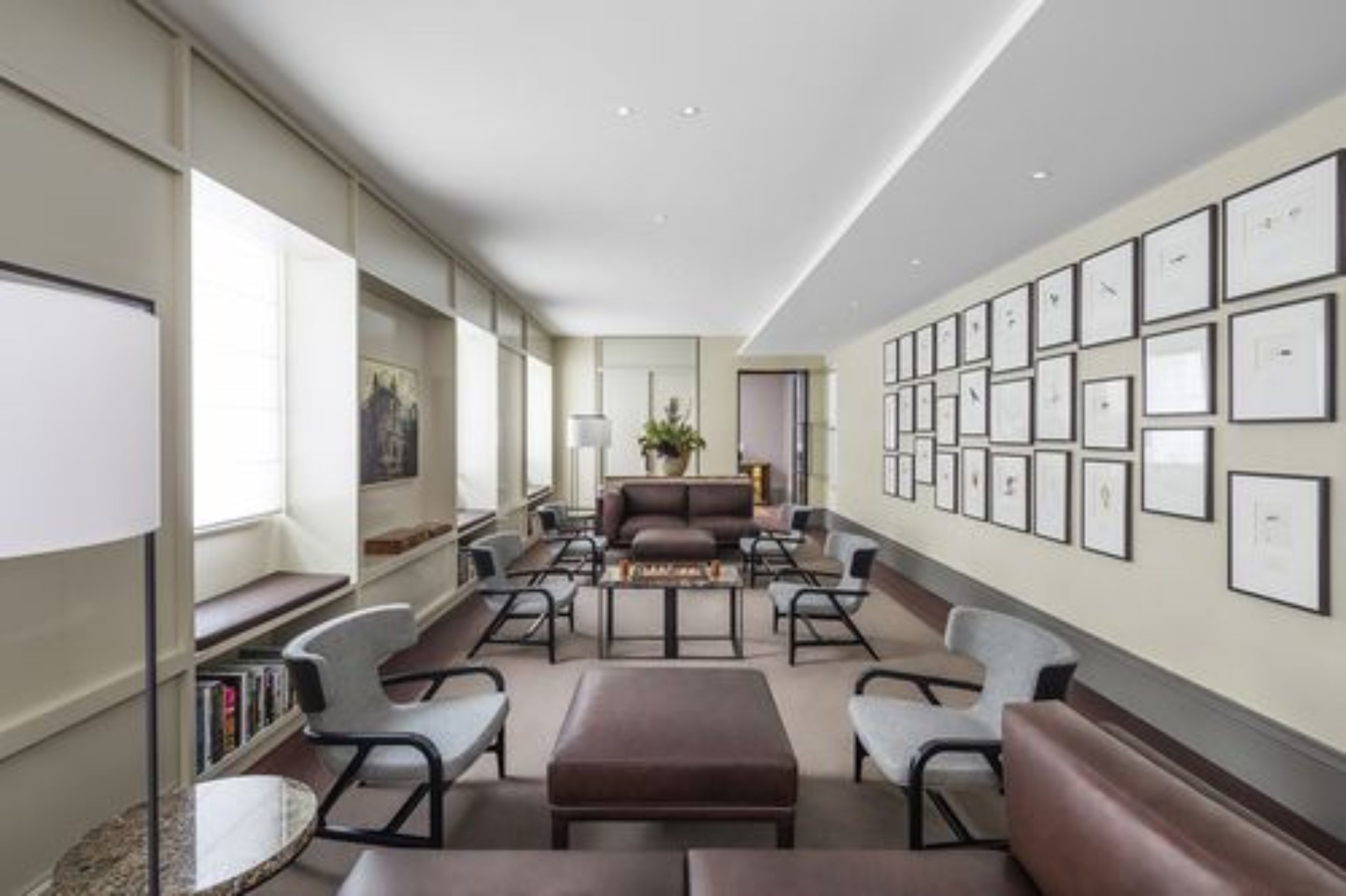 A modern hotel lobby with a long reception desk, comfortable seating, and a wall of framed pictures.