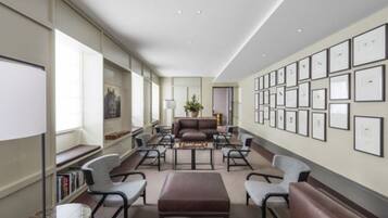 A modern hotel lobby with a long reception desk, comfortable seating, and a wall of framed pictures.