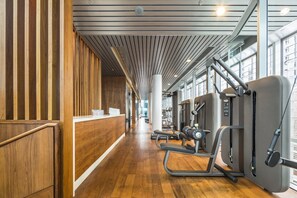A gym with wooden paneling, exercise equipment, and a long corridor.