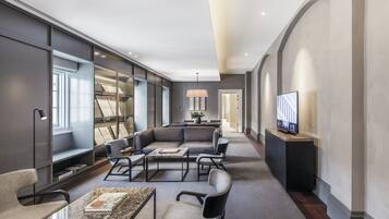 A modern hotel lobby with a seating area, a television, and a large bookshelf.