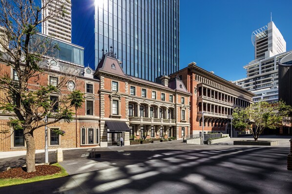 A historic building with a brick facade and large windows, surrounded by modern skyscrapers.